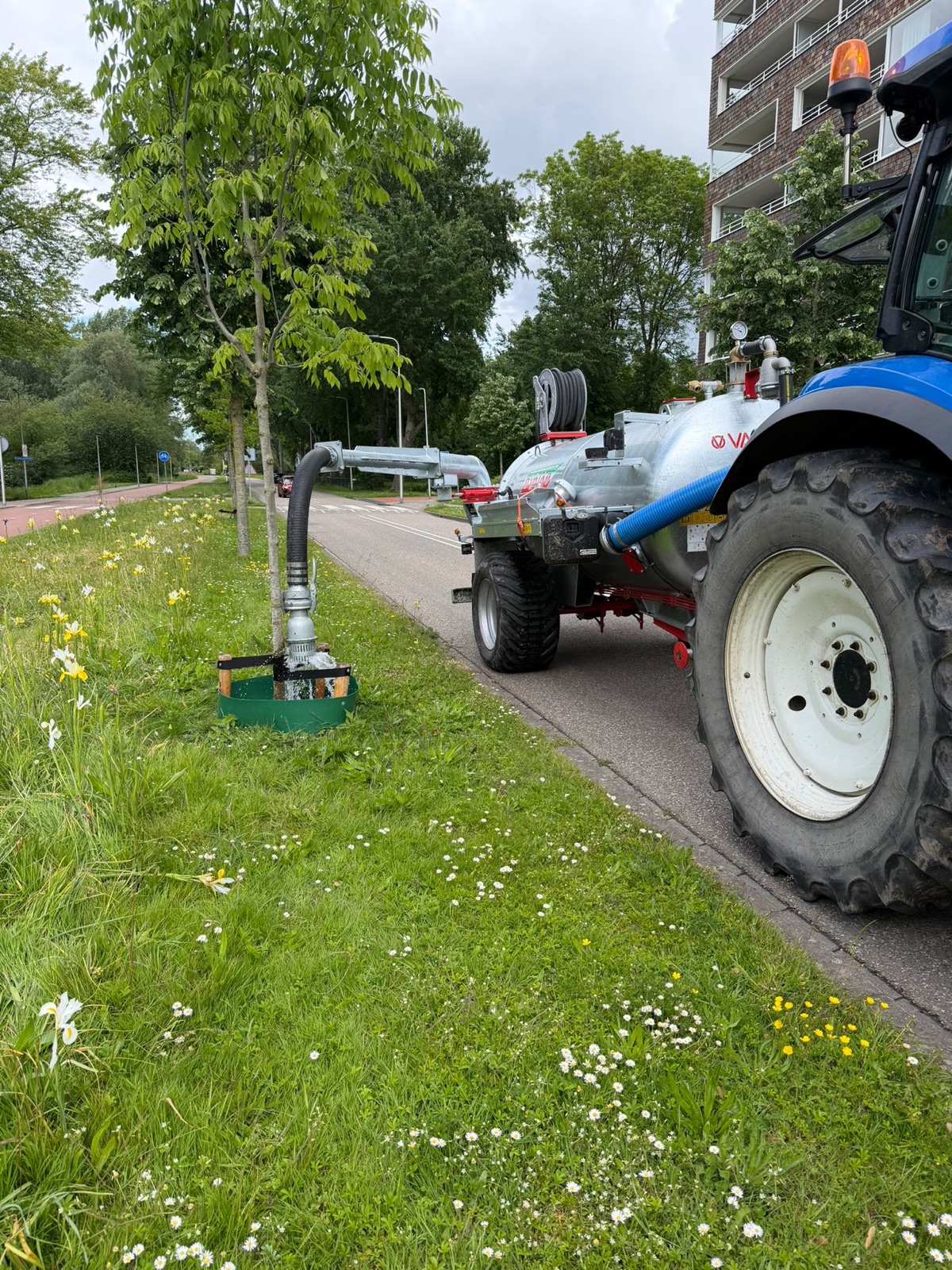 Machinaal water geven aan een jonge boom met gietrand